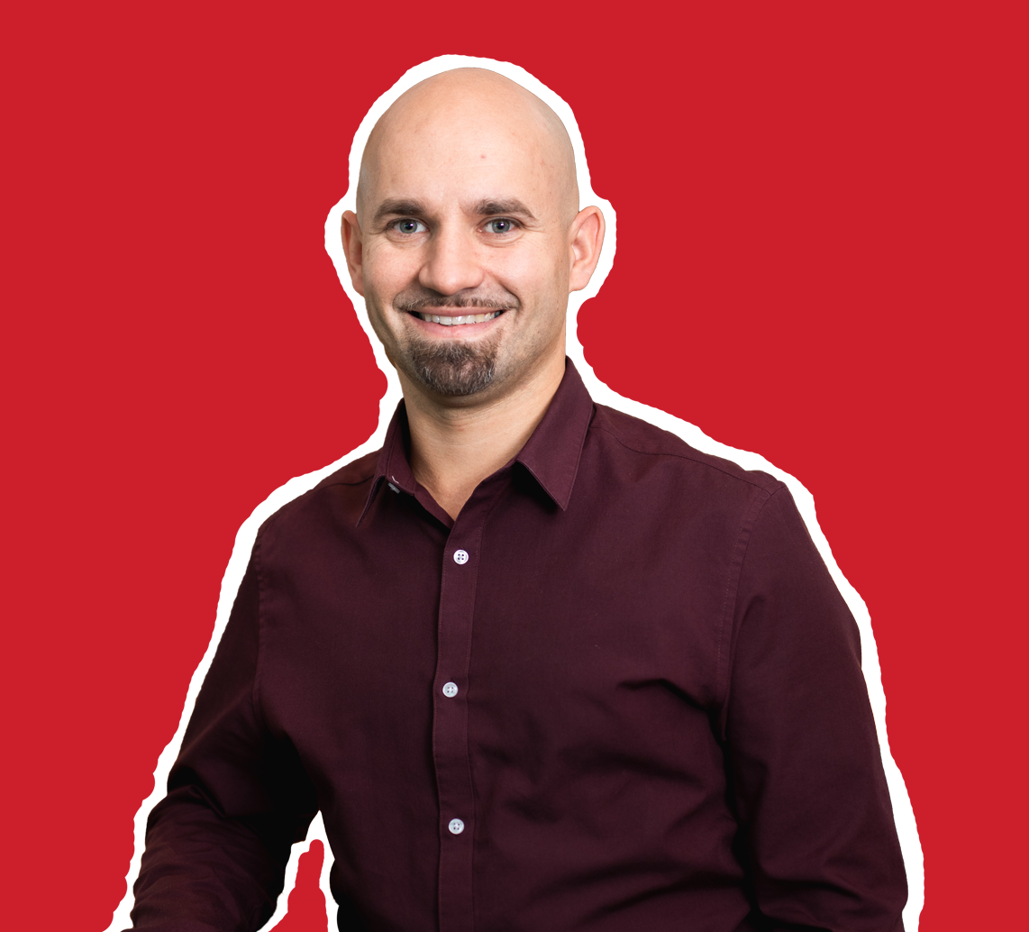 Lächelnder Mann mit Bart in weinrotem Hemd, umrissen vor einem kräftigen roten Hintergrund.