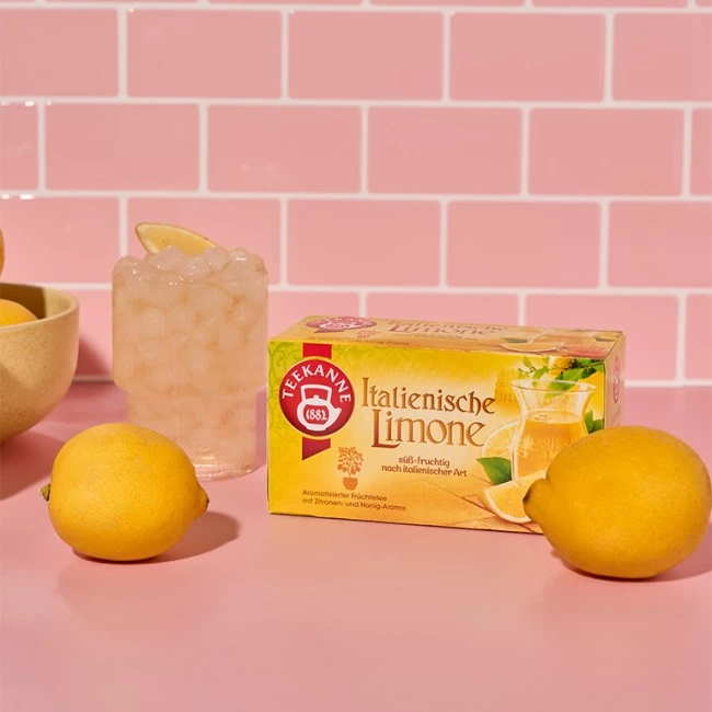 Teekanne Italian Lemon Teebox, frische Zitronen und Zitronen-Eistee auf rosa Untergrund.