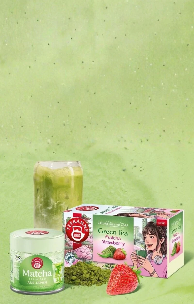 Ein Glas eisgekühlter Matcha-Grüntee, Matcha-Pulver, Erdbeere, Teedose und ein NEU!-Etikett.