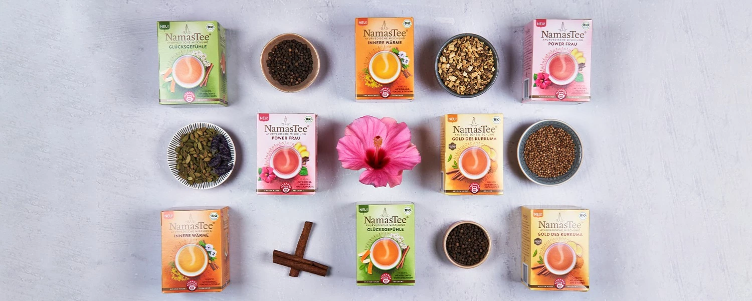 Acht bunte Teeboxen mit Schalen mit losem Tee, Gewürzen, Hibiskusblüten und Zimtstangen.