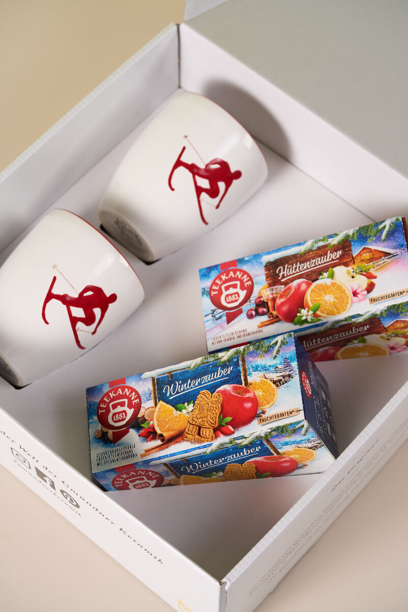 Das Winter-Geschenkset enthält eine weiße Geschenkbox mit zwei weißen Tassen mit Robin Rot Toni Skimotiven und zwei Schachteln EDEKA Winterzauber-Kekse - eine festliche Wahl für Weihnachten.