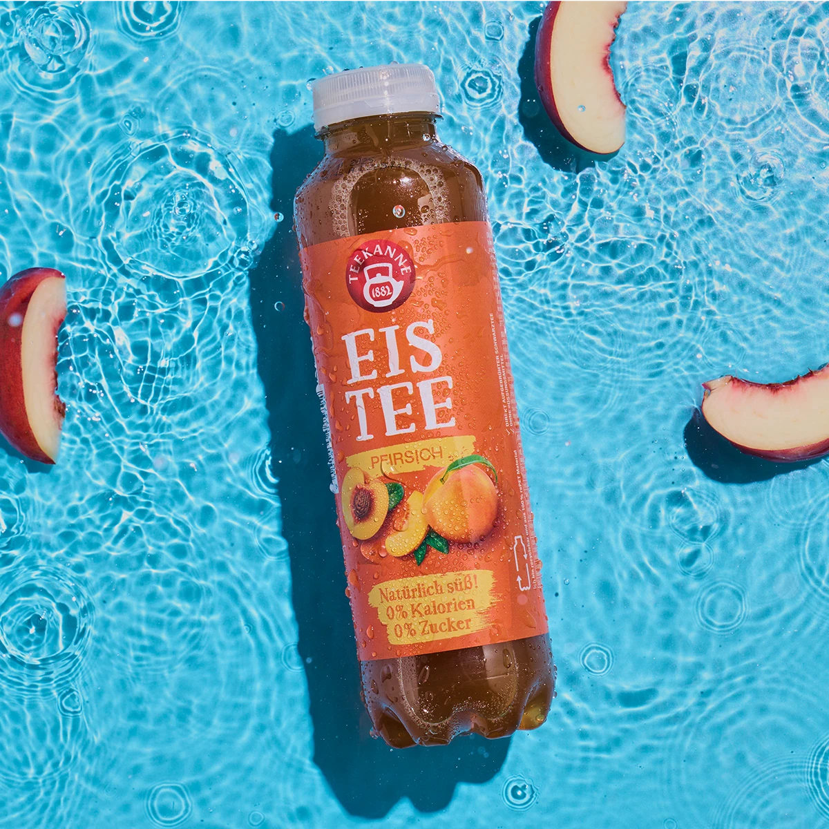 Eine Flasche Pfirsich schwimmt mit Pfirsichscheiben im klaren blauen Wasser. Das orangefarbene Etikett zeigt saftige Pfirsiche und erfrischende Wassertropfen.